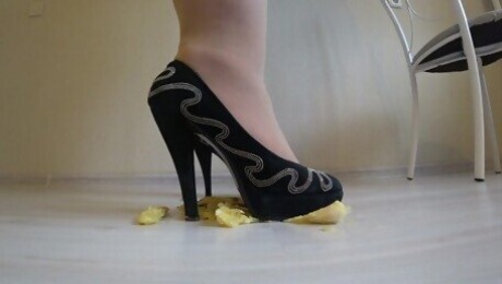 She wears nylon tights, high heels and crushes a banana with her high heels.